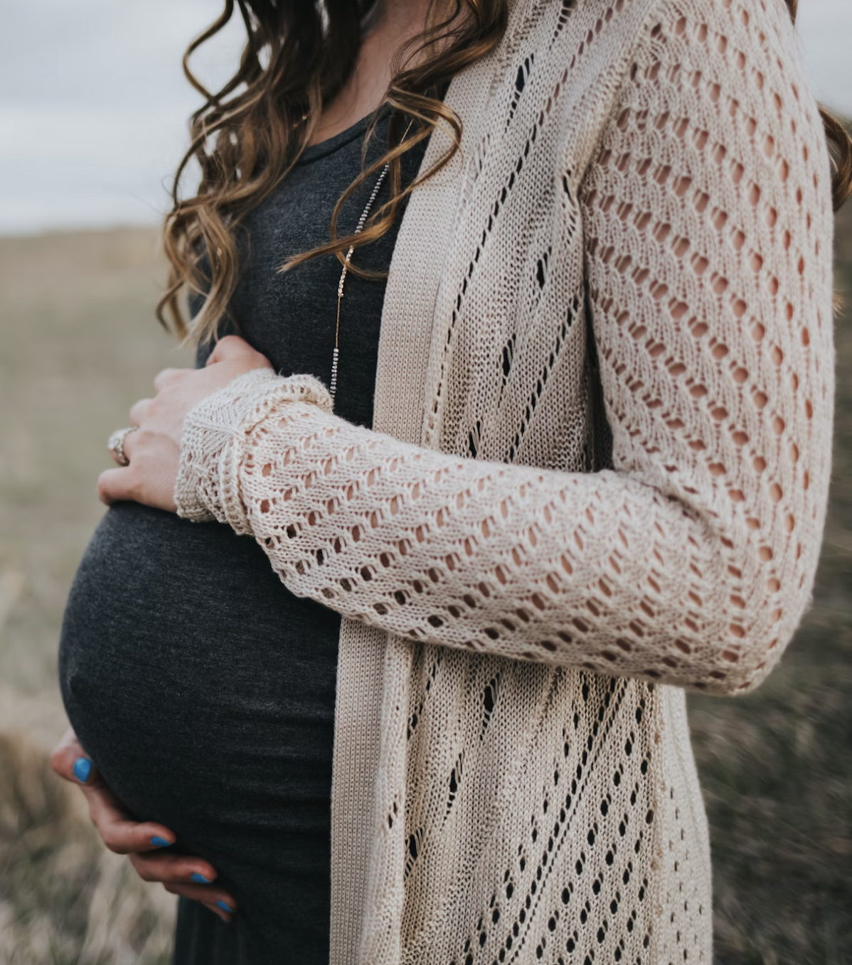 Pregnant Woman in Cardigan Pregnant woman holding her stomach
